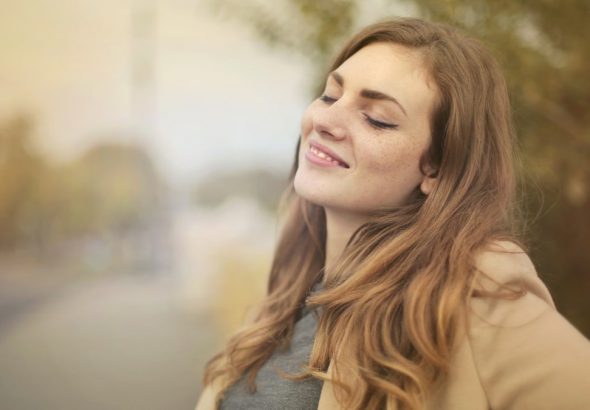 Portrait of a woman with closed eyes, enjoying the outdoors in autumn. Bright and serene.